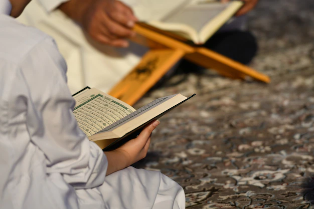 A Muslim man teaches his child how to recite Quran