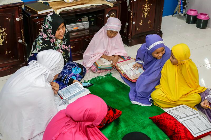 Muslim kids reading the Quran with tutor