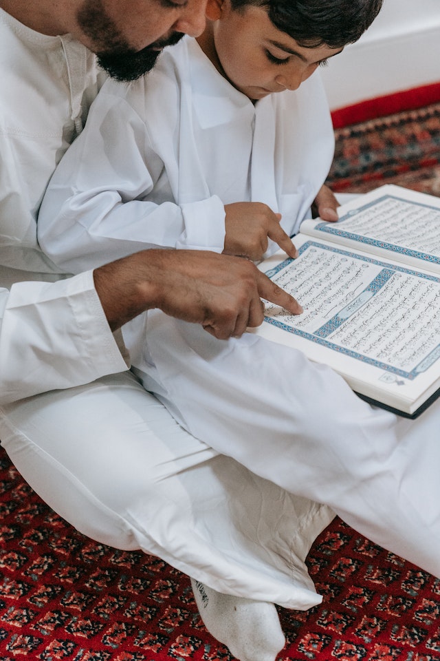 A father, teaching his son to read Quran