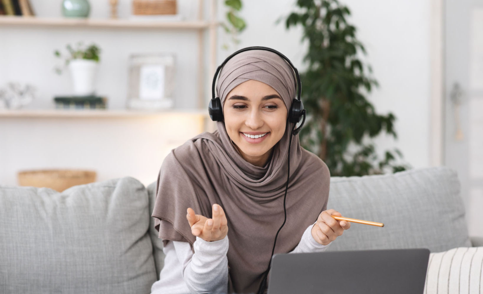 Online Tutoring. Young Muslim woman teacher having video call with students, talking at laptop camera.